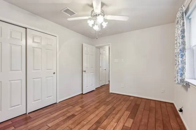 a view of a room with wooden floor and a chandelier fan