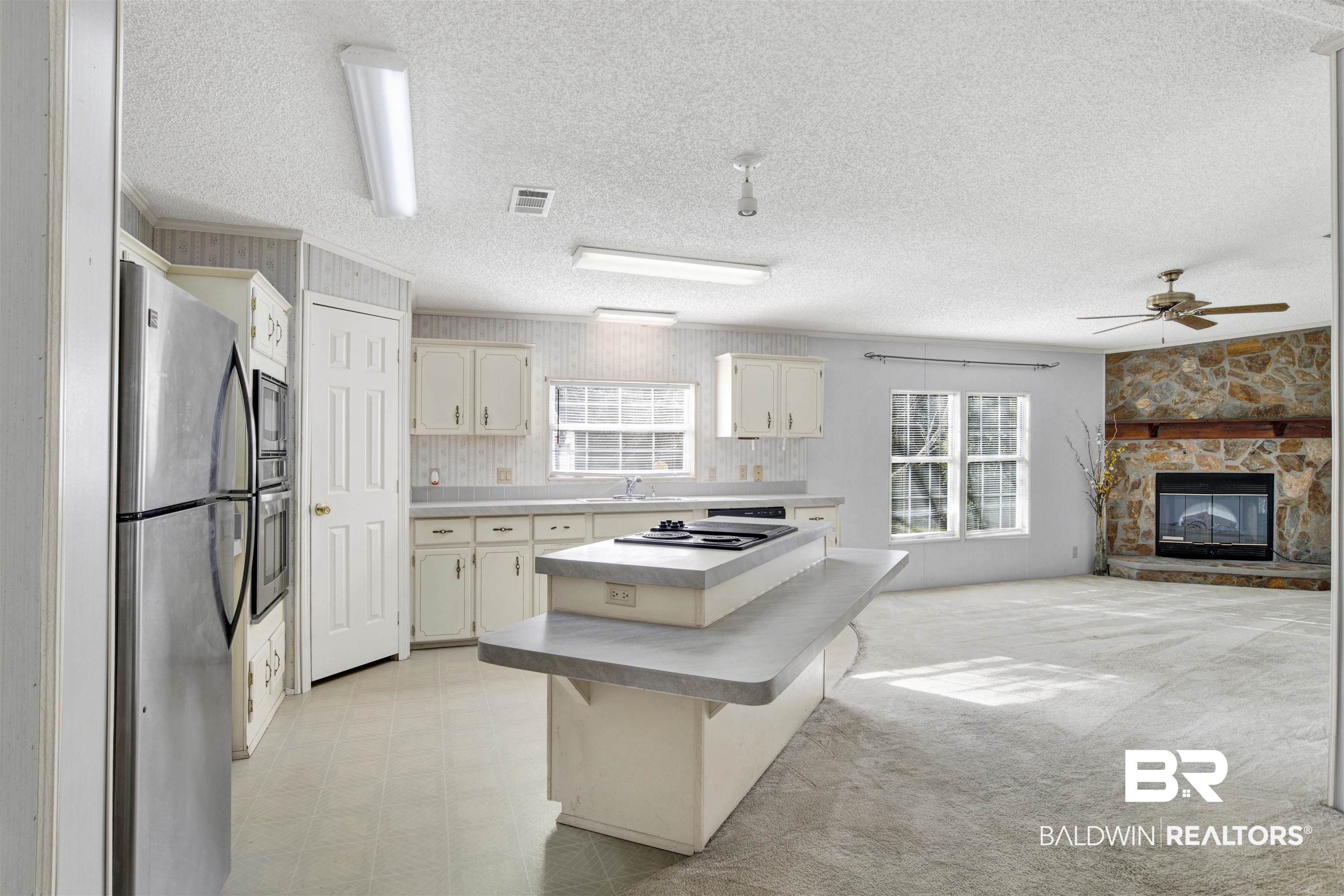 1216 Ridgewood Drive Lillian, AL 36549 - Photo 4 of 29 Kitchen with appliances with stainless steel finishes, a breakfast bar area, light countertops, a center island, and a textured ceiling