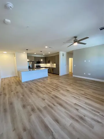 an empty room with wooden floor and a ceiling fan