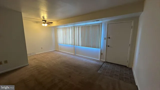 an empty room with a ceiling fan and carpet