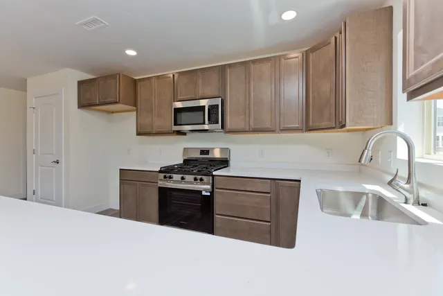 a kitchen with stainless steel appliances kitchen island granite countertop a stove a sink and a microwave