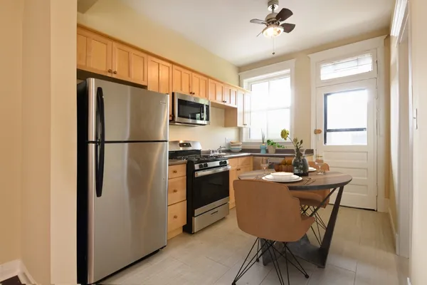 a kitchen with stainless steel appliances granite countertop a refrigerator a sink a stove a dining table and chairs