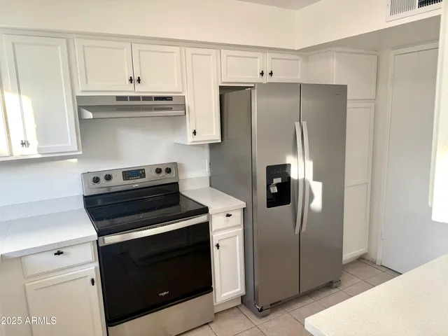 a kitchen with stainless steel appliances white cabinets and a refrigerator