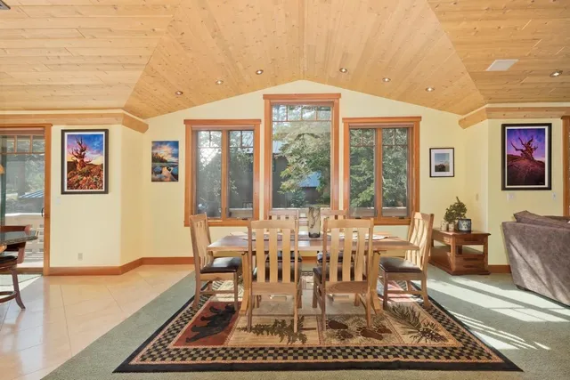 a dining room with wooden floor a rug and a floor to ceiling window