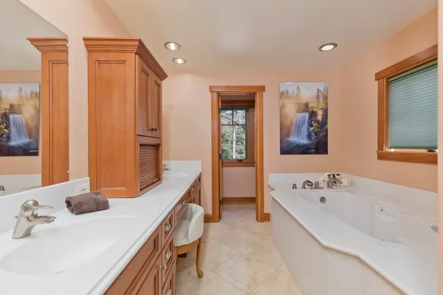 a bathroom with a tub a sink and mirror