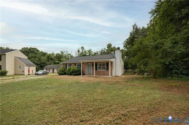 a front view of house with yard and trees in the background