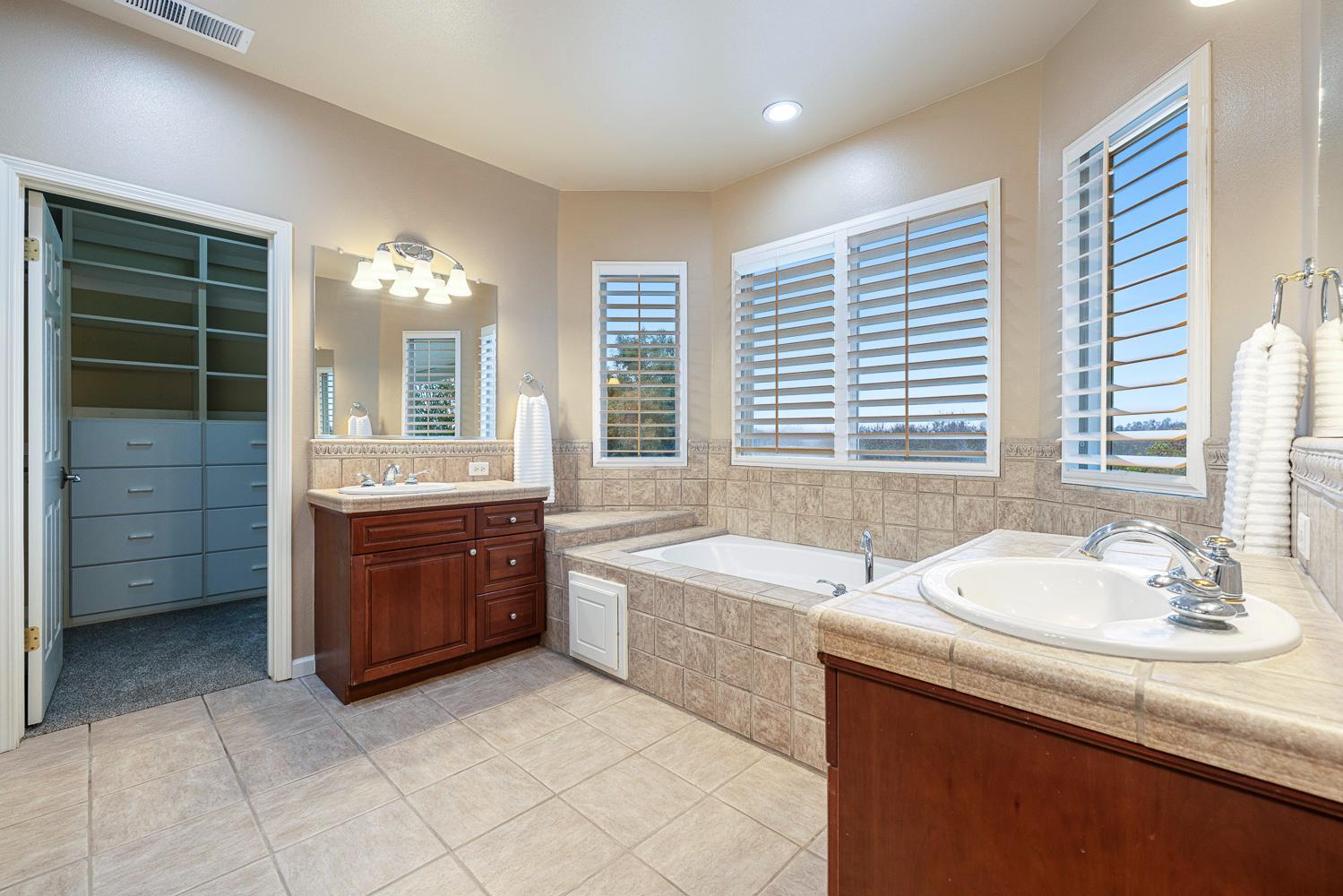 4674 North Arrow Ridge Way Clovis, CA 93619 - Photo 49 of 77 a spacious bathroom with a sink mirror and a bathtub