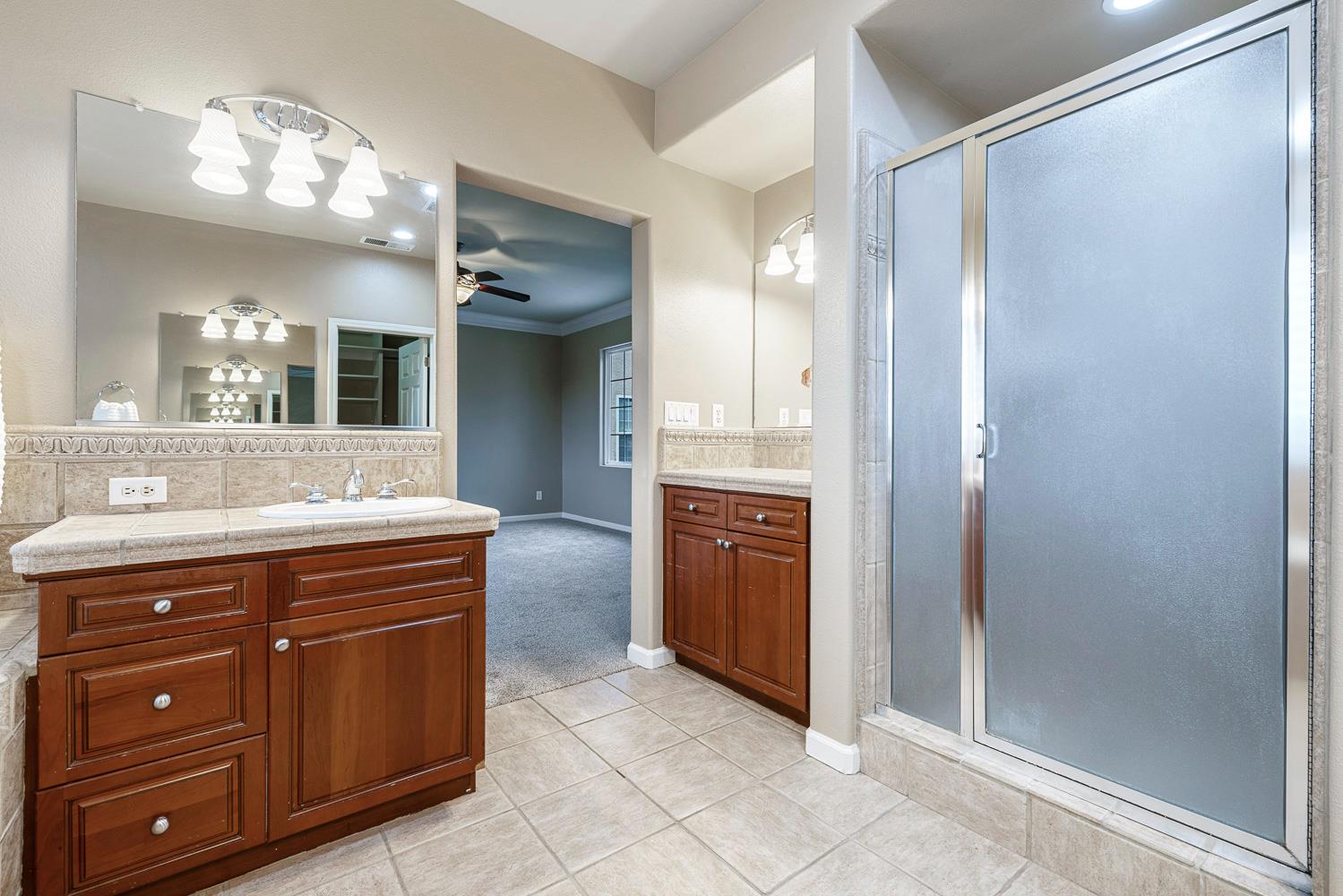 4674 North Arrow Ridge Way Clovis, CA 93619 - Photo 51 of 77 a bathroom with a granite countertop sink a mirror and a shower