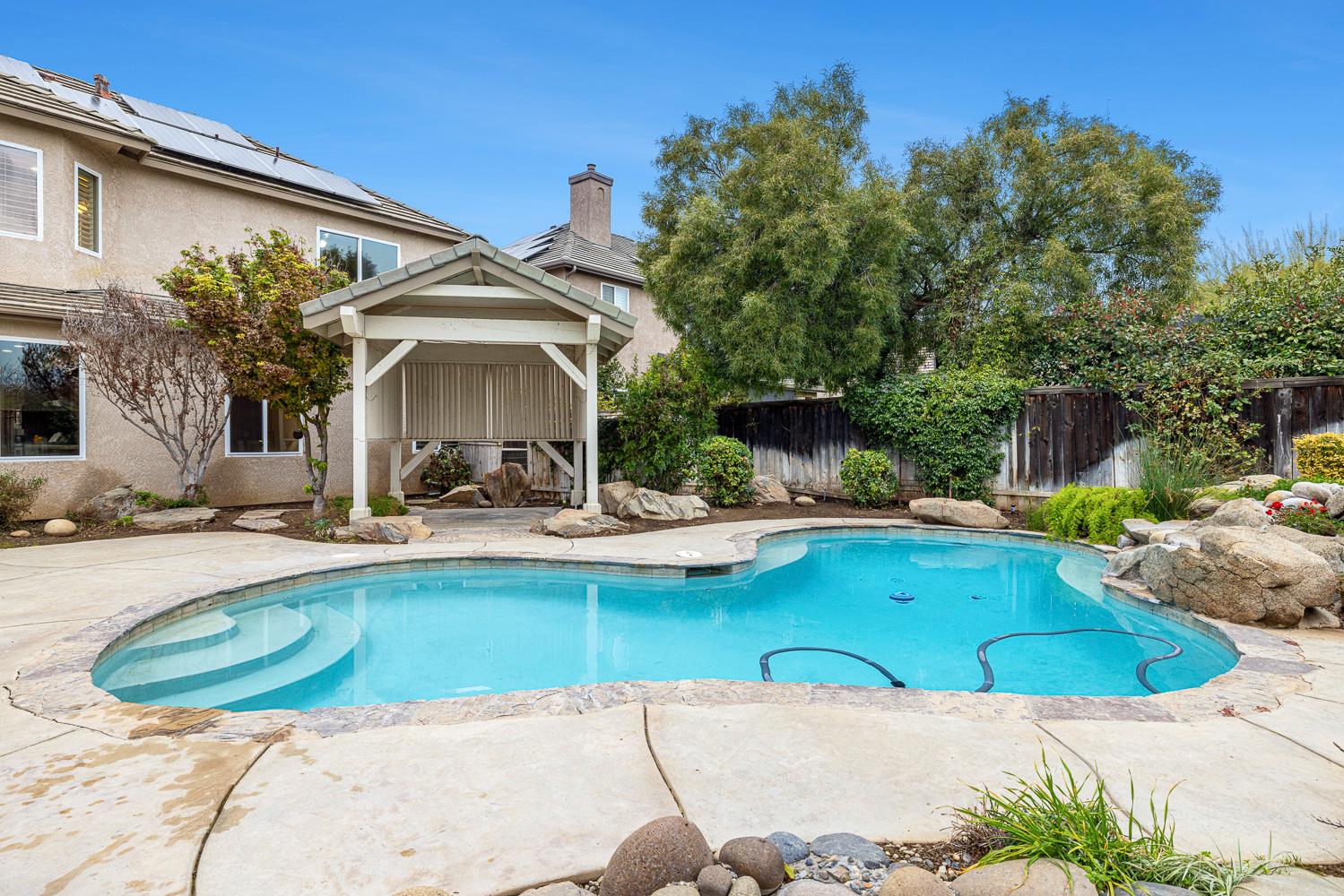 4674 North Arrow Ridge Way Clovis, CA 93619 - Photo 58 of 77 a view of a swimming pool with statues and a chairs