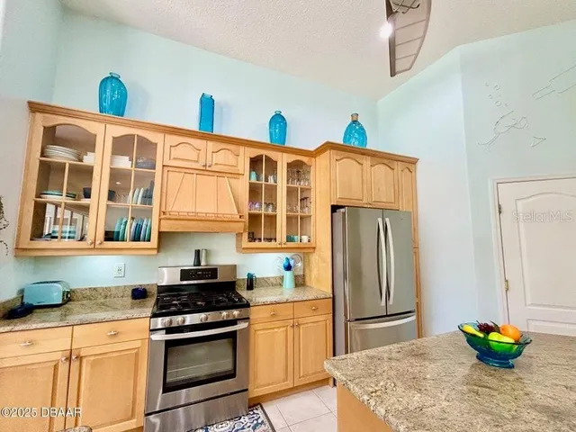 a kitchen with stainless steel appliances granite countertop a refrigerator a stove and a sink