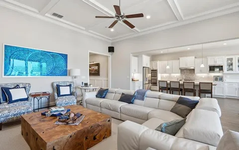 a living room with furniture kitchen view and a chandelier