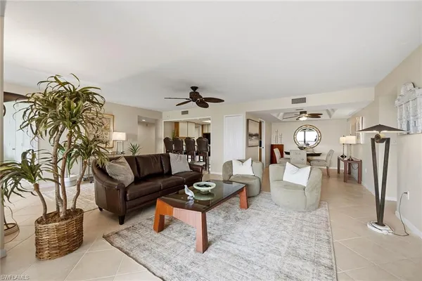 a living room with furniture a chandelier and a dining table with wooden floor