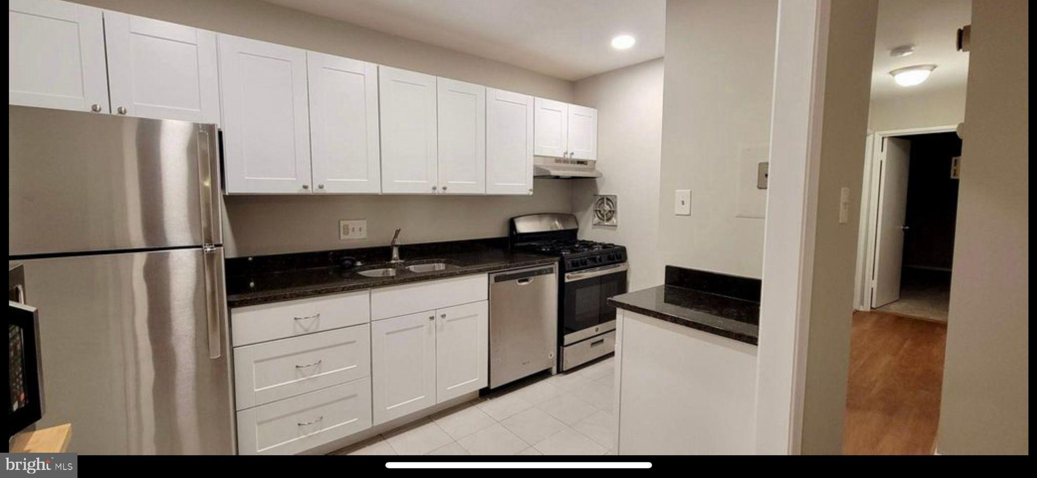 a kitchen with stainless steel appliances granite countertop a refrigerator sink and white cabinets
