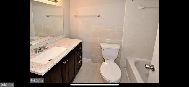 a bathroom with a granite countertop toilet and a sink