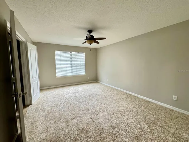 an empty room with windows and a ceiling fan
