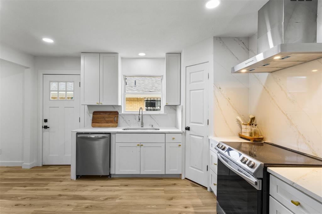 1917 South Vernon Avenue Dallas, TX 75224 - Photo 9 of 28 Modern kitchen featuring white shaker cabinetry, gold-tone hardware, stainless steel appliances, a white sink, and wood-finish flooring