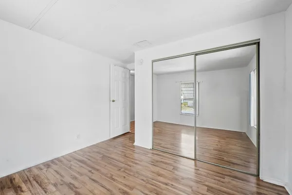 a view of an empty room with wooden floor and closet