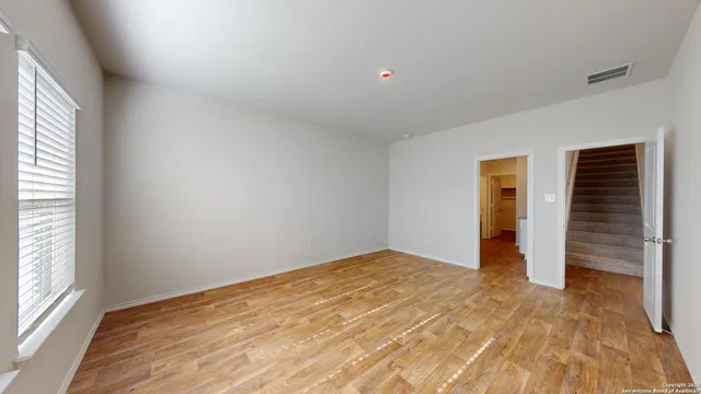 a view of an empty room with wooden floor and a window