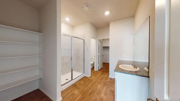 a bathroom with a granite countertop sink a mirror and shower