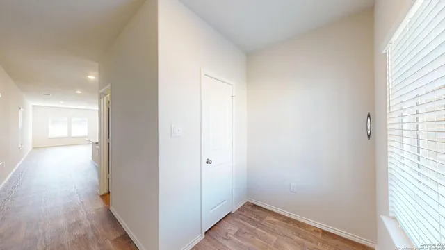 a view of a hallway with wooden floor and a window