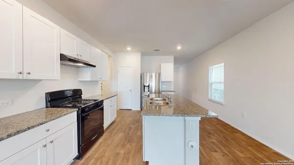 a kitchen with granite countertop a sink a stove refrigerator and cabinets