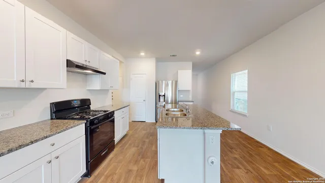 a kitchen with granite countertop a sink a stove refrigerator and cabinets