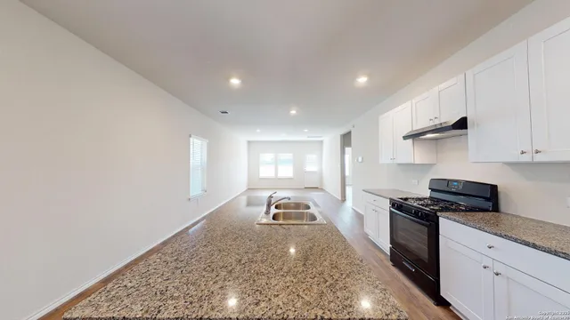 a kitchen with granite countertop stainless steel appliances a stove top oven a sink a counter space and cabinets