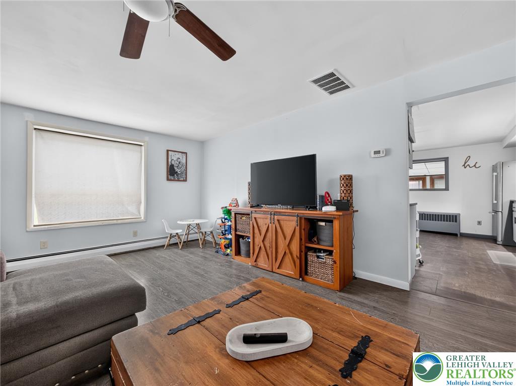 2628 Levans Road Coplay, PA 18037 - Photo 12 of 54 A casual living space features wood-look flooring and a functional ceiling fan for optimal comfort.