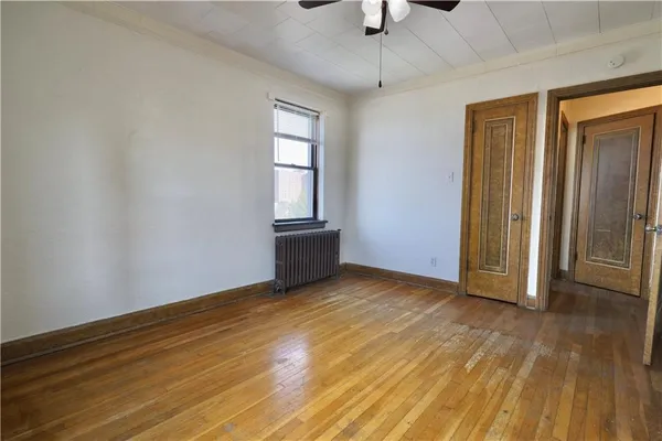 an empty room with wooden floor cabinet and windows