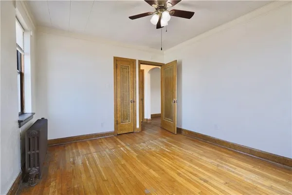 an empty room with wooden floor chandelier fan and closet