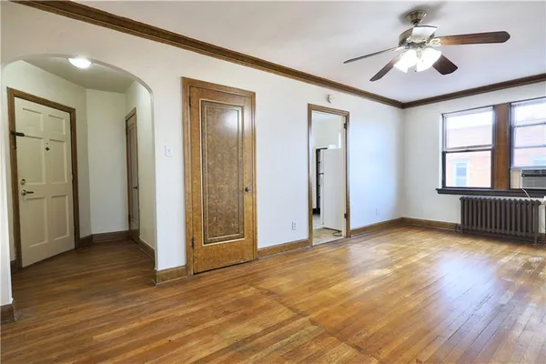 a view of an empty room with window and wooden floor