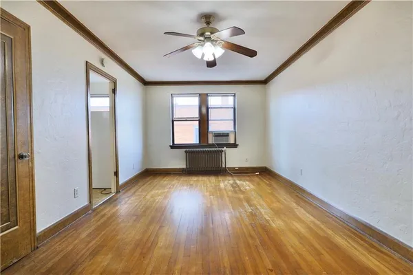 a view of empty room with wooden floor and fan