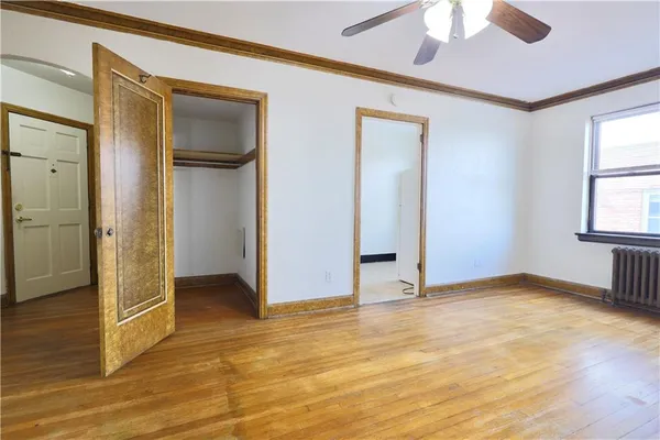 a view of an empty room with window and wooden floor
