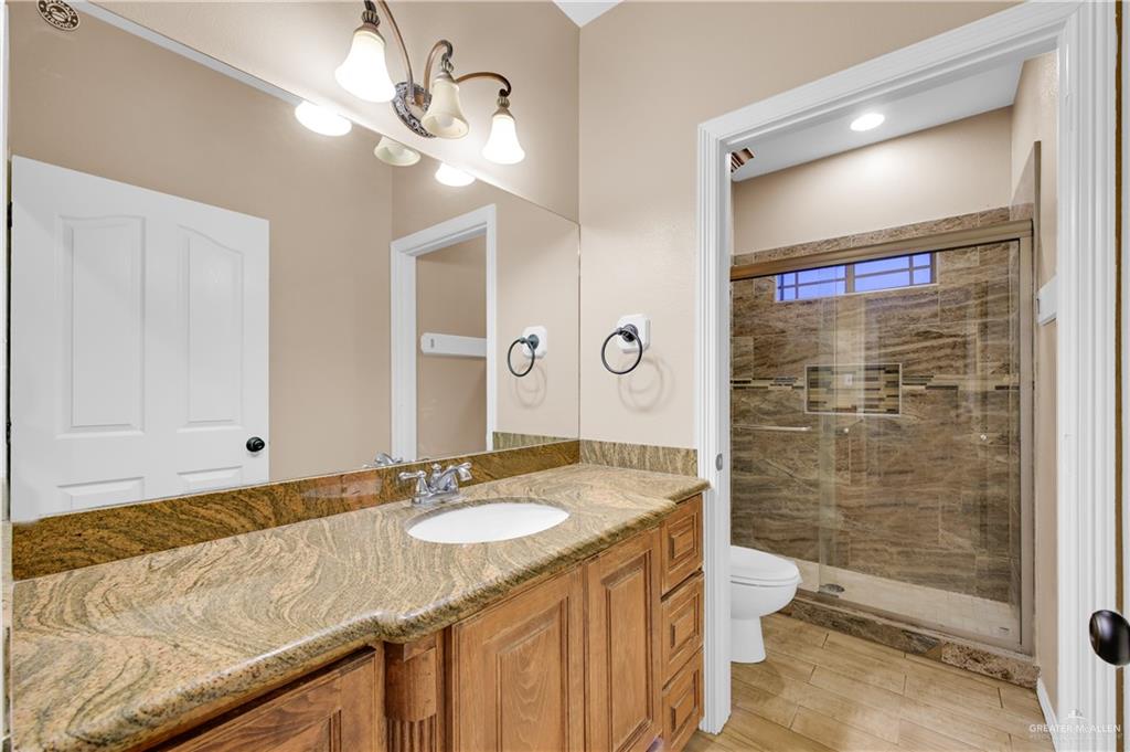 2005 Stuart Road Weslaco, TX 78599 - Photo 18 of 30 a bathroom with a granite countertop sink a toilet a mirror and shower