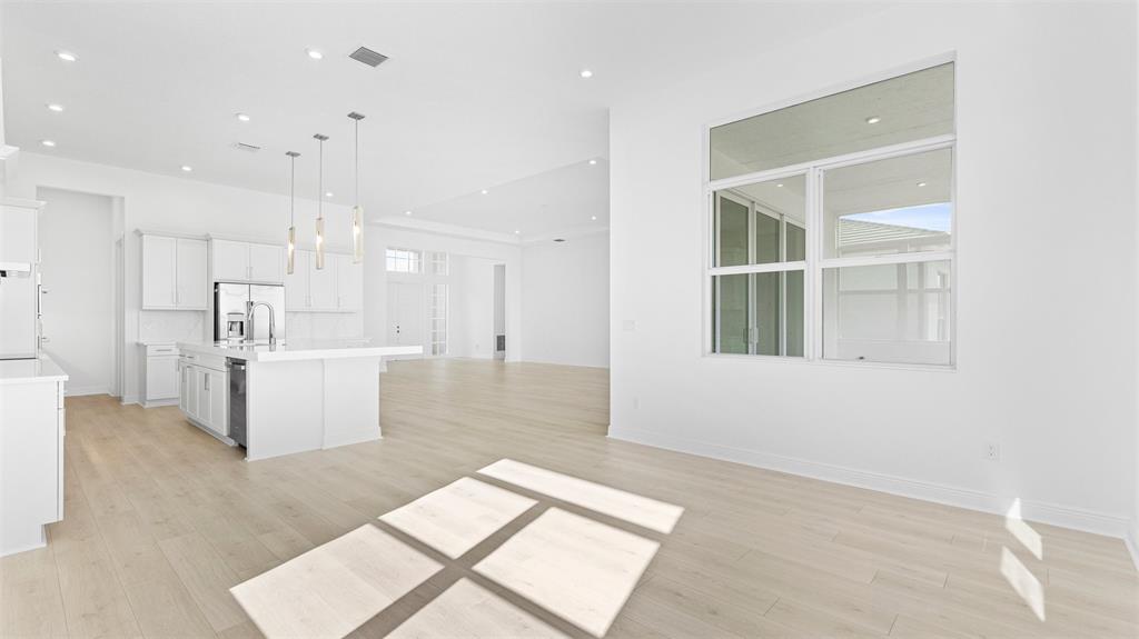 8447 Southwest Felicita Way Port St. Lucie, FL 34987 - Photo 16 of 92 a large white room with kitchen view and wooden floor