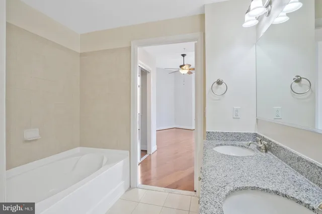 a bathroom with a granite countertop sink a mirror and bathtub
