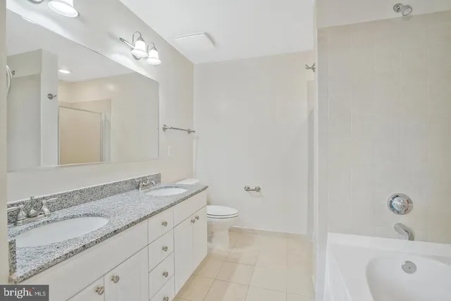a bathroom with a granite countertop sink a toilet and a mirror