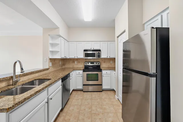 a kitchen with stainless steel appliances granite countertop a refrigerator and a sink