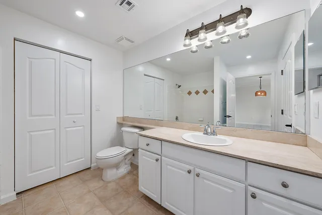 a spacious bathroom with a granite countertop sink a toilet and a mirror