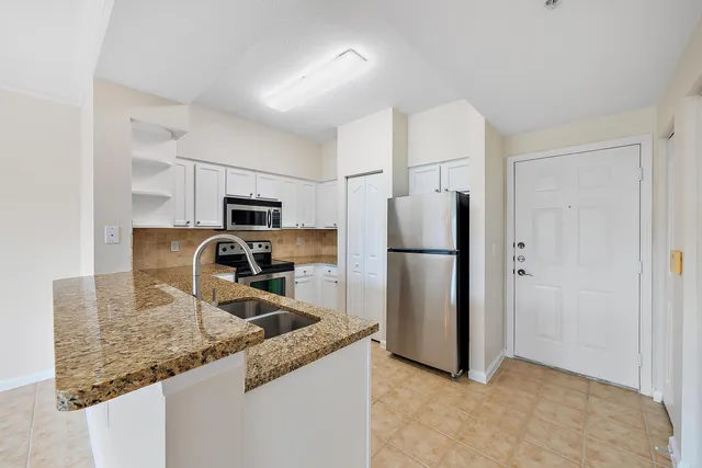 a kitchen with granite countertop a refrigerator and a sink