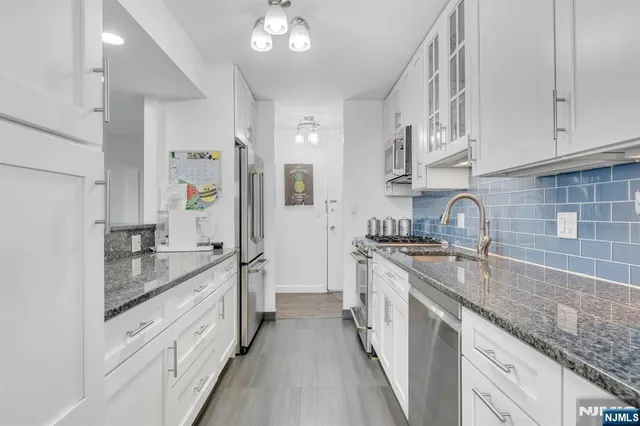 a kitchen with stainless steel appliances granite countertop a sink and a refrigerator