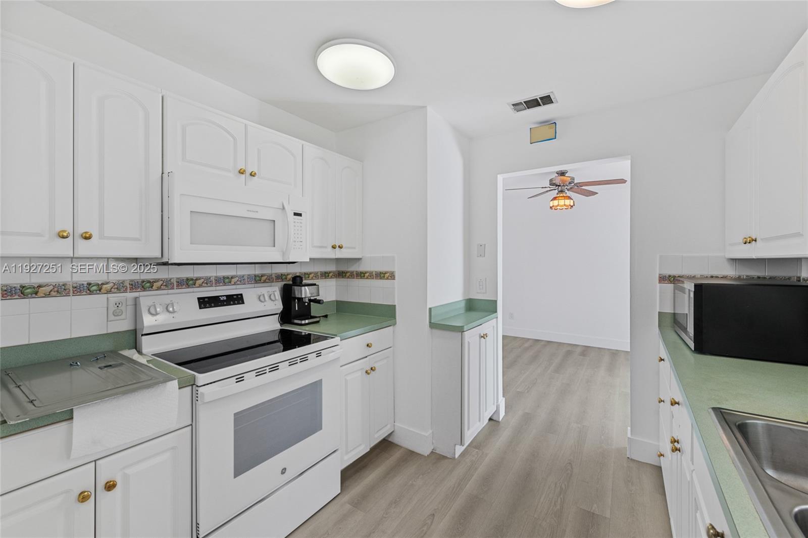9864 Southwest 26th Terrace Miami, FL 33165 - Photo 13 of 40 a kitchen with white cabinets and white appliances