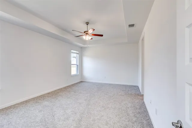 an empty room with chandelier fan and windows