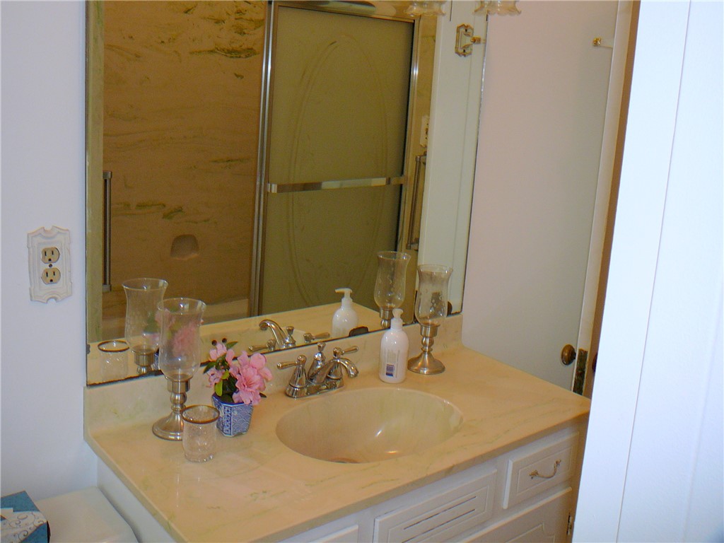 411 Central Avenue Anderson, SC 29625 - Photo 15 of 23 This bright bathroom features a vanity with a sink and a mirror, complemented by a nearby shower.