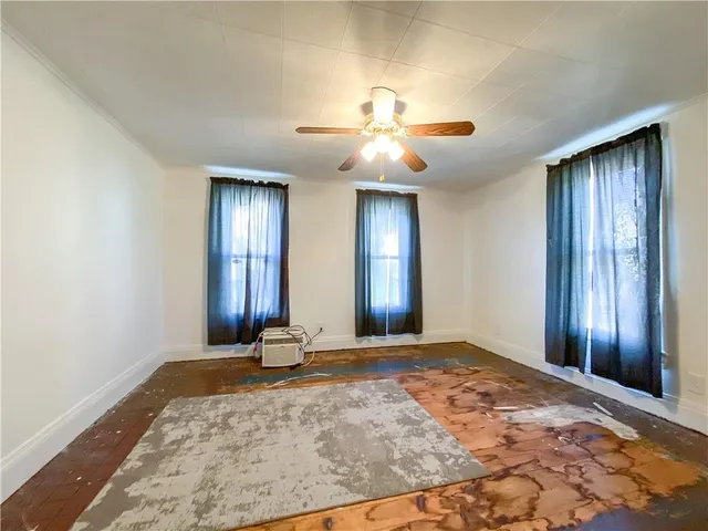 an empty room with a chandelier fan and windows