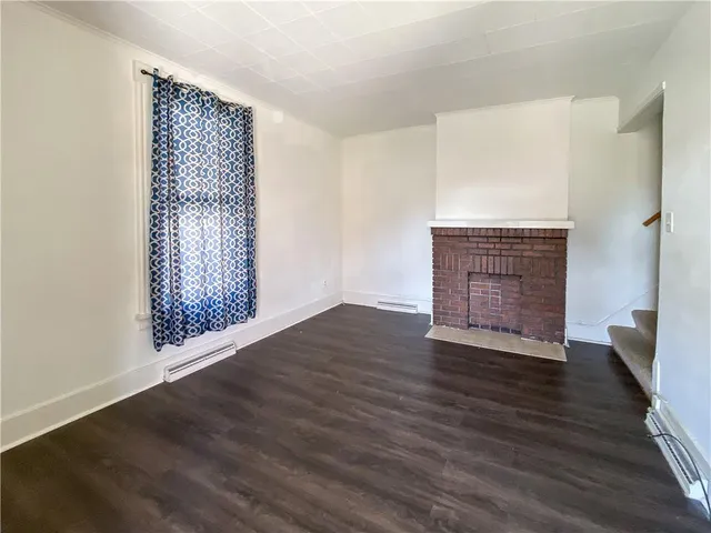 an empty room with wooden floor cabinet and windows