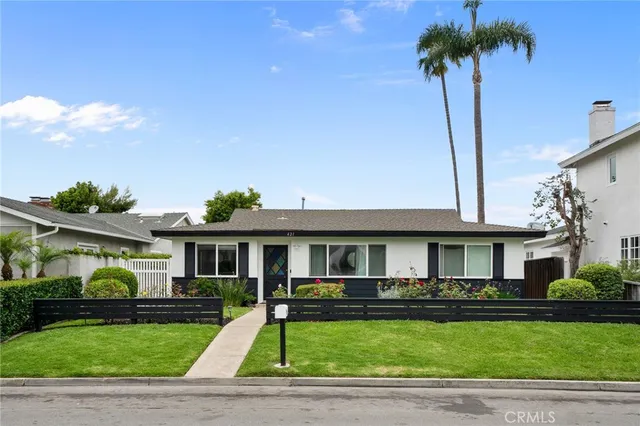 a front view of a house with a garden and trees