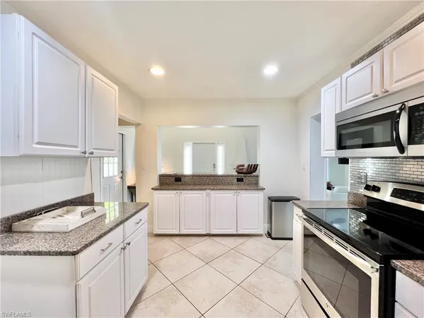 a kitchen with granite countertop a sink stainless steel appliances and white cabinets