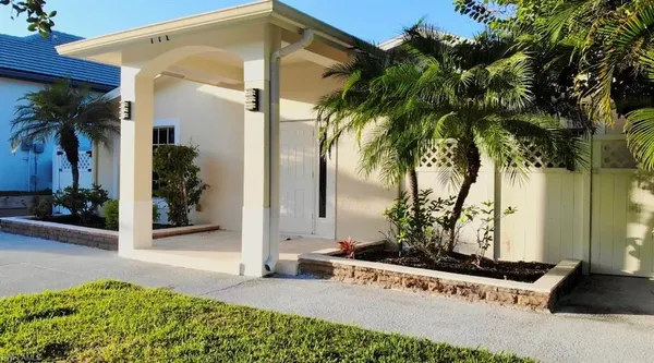 a view of a house with a yard and potted plants