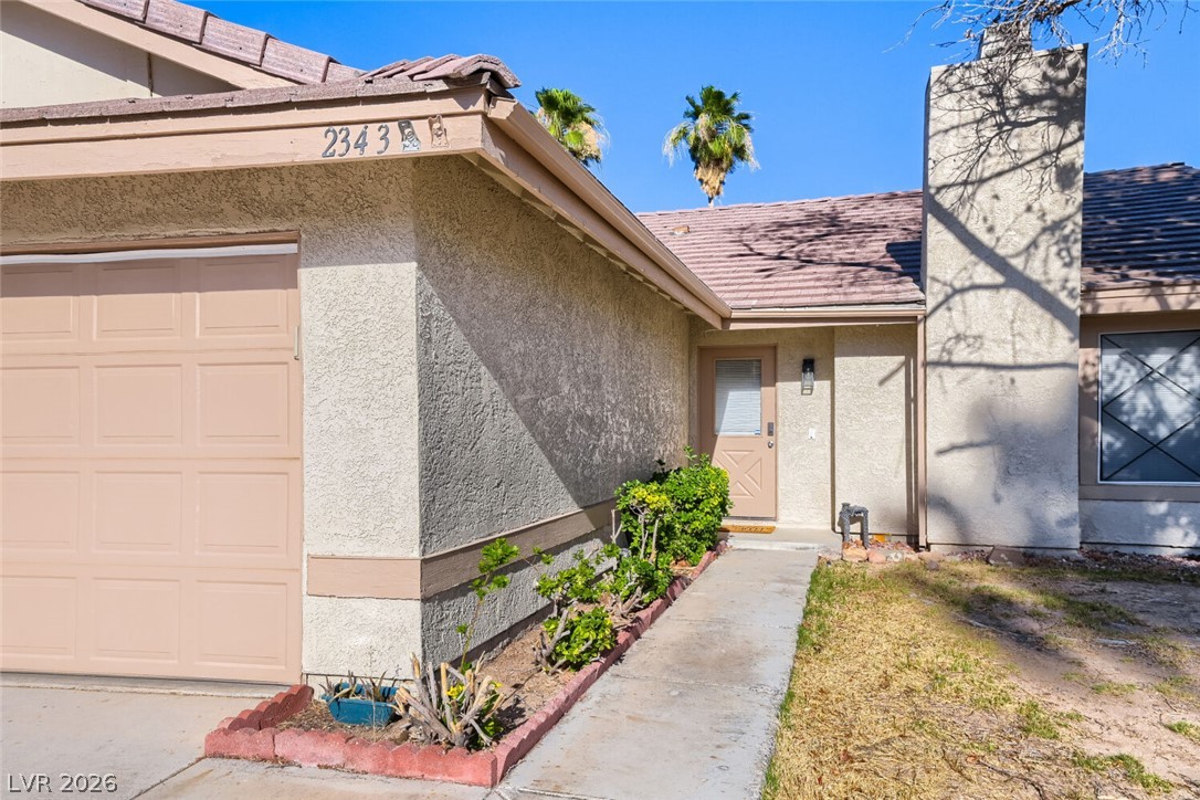 2343 Valleywood Road Henderson, NV 89014 - Photo 3 of 29 A classic stucco home with an attached garage and a neatly maintained walkway.